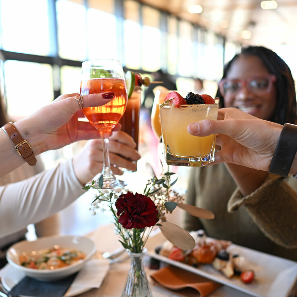 Four friends cheering their glasses at the National Aviary's Brunch in The Garden Room